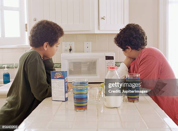 two boys waiting for microwave oven to finish cooking - microwave photos et images de collection