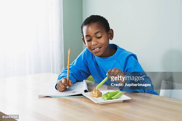 boy eating peanut butter and celery - bleekselderij stockfoto's en -beelden