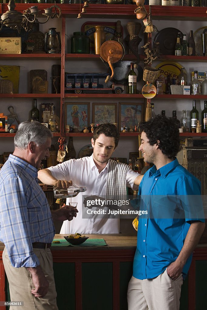 Bartender serving aguardiente to men