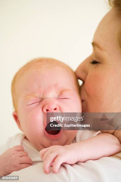 mother kissing yawning infant daughter - good morning kiss images stock-fotos und bilder