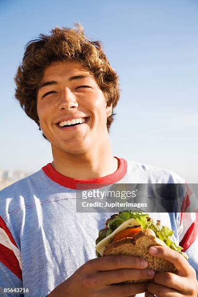 smiling teen boy holding sandwich - headshot of a teen boy stockfoto's en -beelden