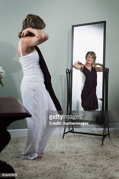 woman holding dress and looking in mirror - full length mirror fotografías e imágenes de stock