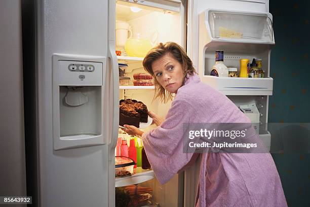 woman taking cake out of refrigerator - chocolate cake foto e immagini stock