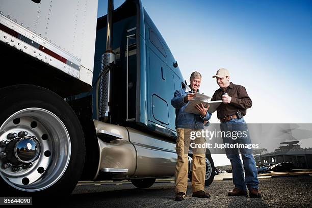 men looking at paperwork near tractor trailer - flatbed truck stock-fotos und bilder