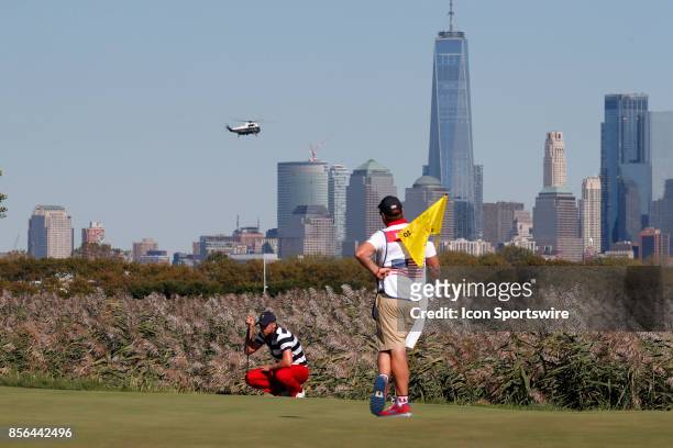 Golfer Daniel Berger putts on the 10th hole as the presidential helicopter flies over the Manhattan skyline as Donald Trump the 45th president of the...