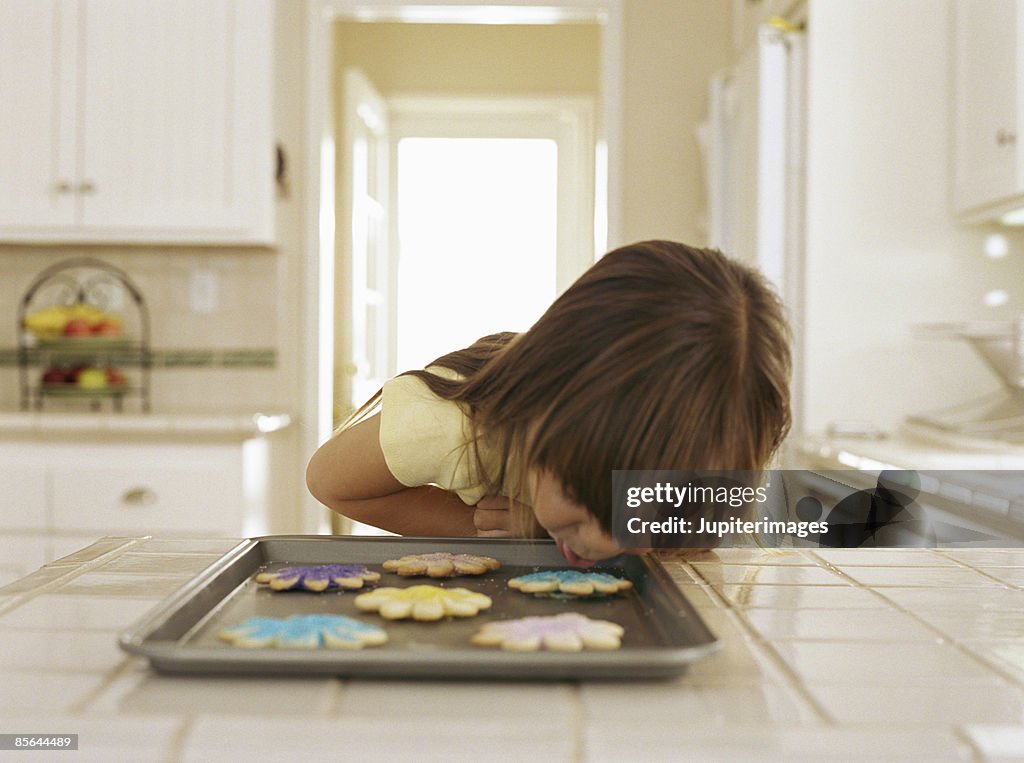 Girl leaning close to cookie sheet