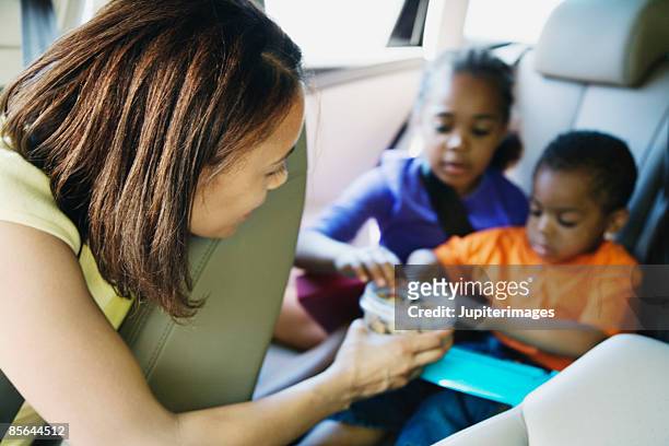 mother and kids in car - snacking stockfoto's en -beelden