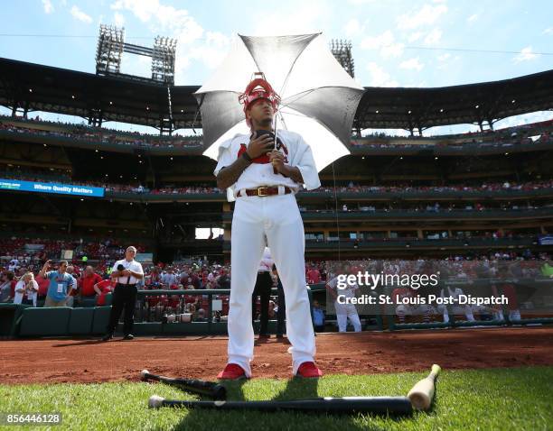 St. Louis Cardinals pitcher Carlos Martinez settles in with an umbrella and catcher's mask as he partakes in a national anthem standoff against...