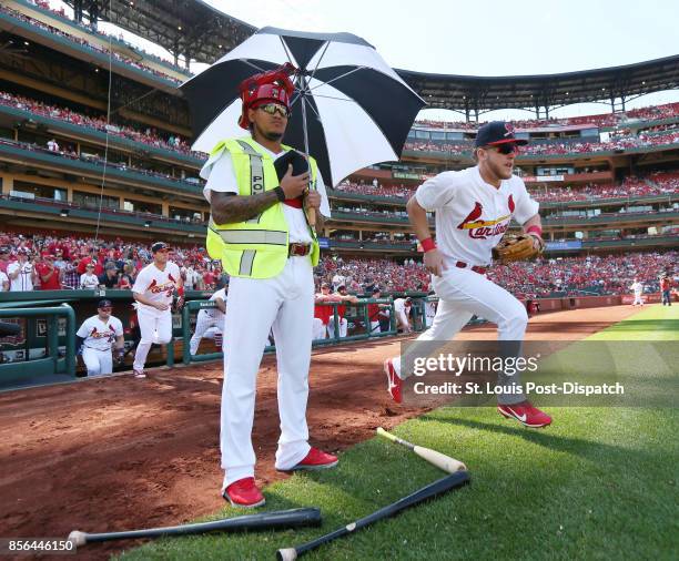 St. Louis Cardinals pitcher Carlos Martinez remains on the edge of the grass as center fielder Harrison Bader and teammates take the field before a...