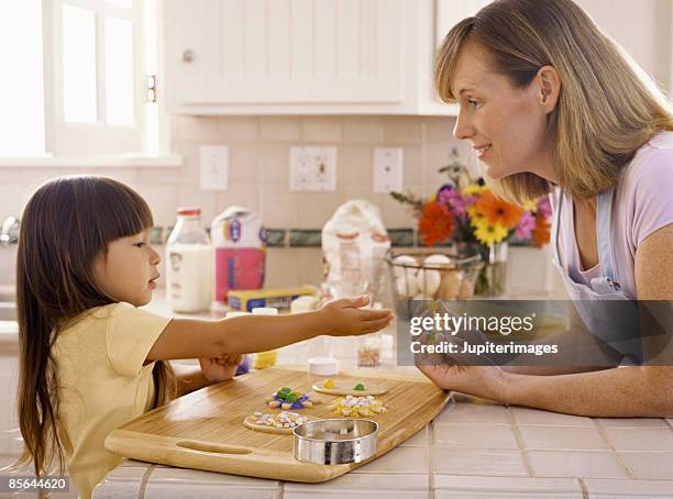 mother and daughter decorating cookies - biscuit au sucre photos et images de collection