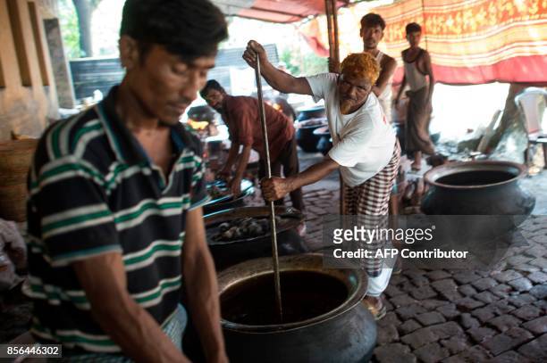 In this picture taken on October 1 Bangladeshi men cook food in pots for Rohingya Muslim refugees at Balukhali refugee camp near the town of Gumdhum...