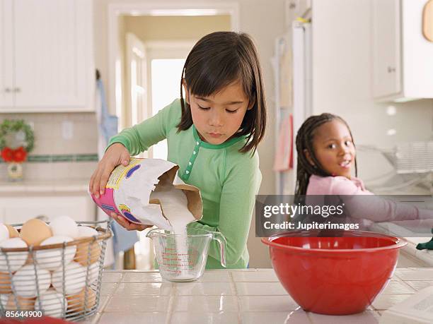 two girls in kitchen baking - measuring cup imagens e fotografias de stock