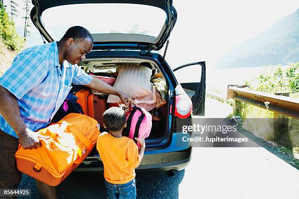 father and son loading car - holiday packing stockfoto's en -beelden