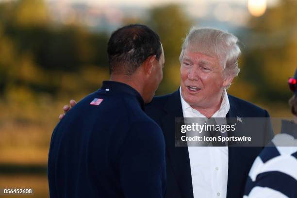 Donald Trump the 45th president of the United States talks to USA vice captain Tiger Woods after the final round of the Presidents Cup at Liberty...