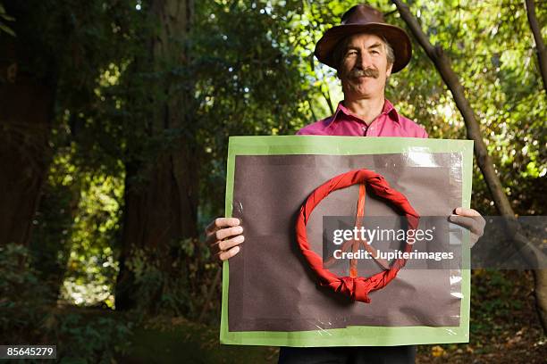 man in woods holding sign with peace symbol - non violence stock pictures, royalty-free photos & images
