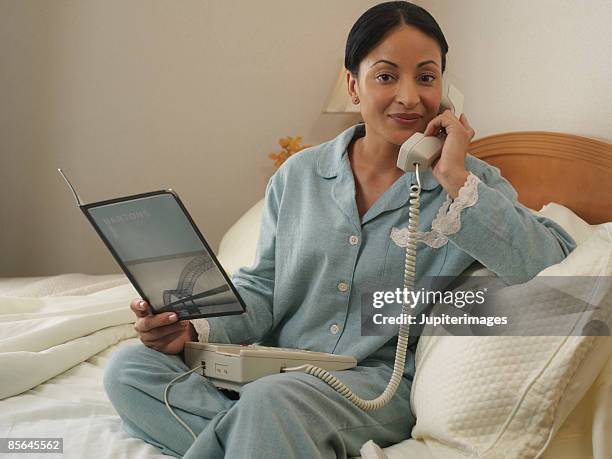 woman in hotel room ordering room service - roomservice stockfoto's en -beelden