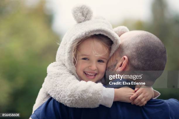 happy child in hooded bear costume, hugging father - headwear stock-fotos und bilder