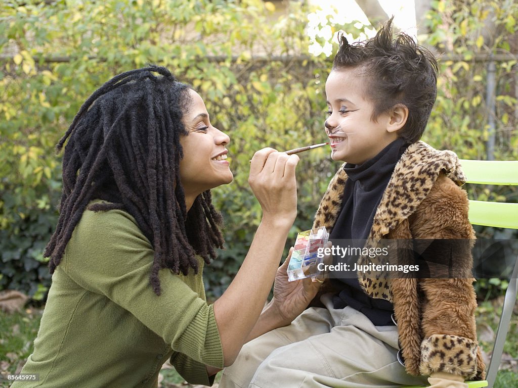 Mother putting makeup on son