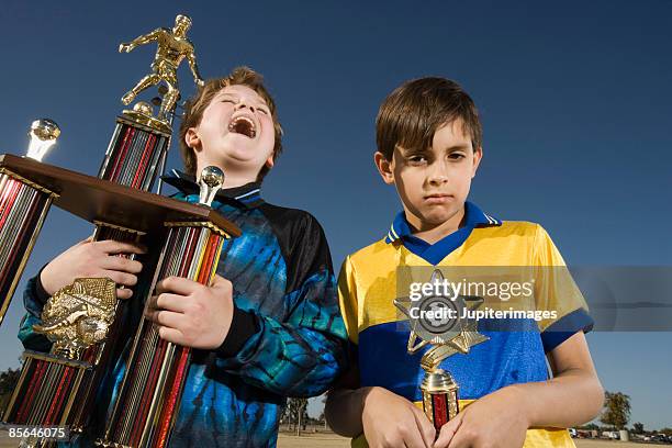 winner and loser holding soccer trophies - first place second place stock pictures, royalty-free photos & images