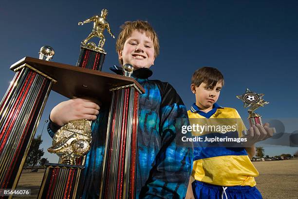winner and loser holding soccer trophies - second place stock pictures, royalty-free photos & images