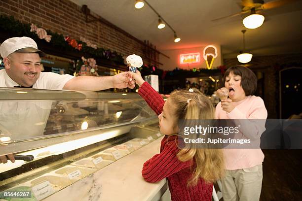 man behind counter giving girl ice cream cone - ice cream counter stock-fotos und bilder