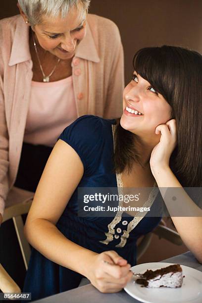 girl and woman engaged in conversation while eating slice of chocolate cake - chocolate souffle stock pictures, royalty-free photos & images