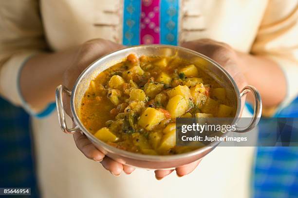 woman holding dish of aloo ki bhaji - pratos vegetarianos imagens e fotografias de stock