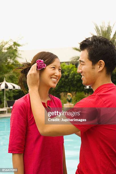 man placing flower in woman's hair - positioned stock pictures, royalty-free photos & images