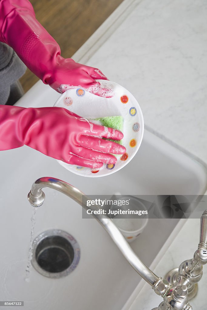 Person washing dishes in kitchen sink