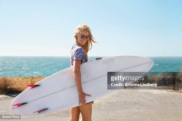 woman by the sea with surfboard - beach hold surfboard stock-fotos und bilder