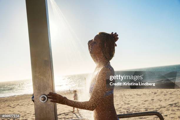 woman showering at the beach at sun down - taking a shower at the beach stockfoto's en -beelden