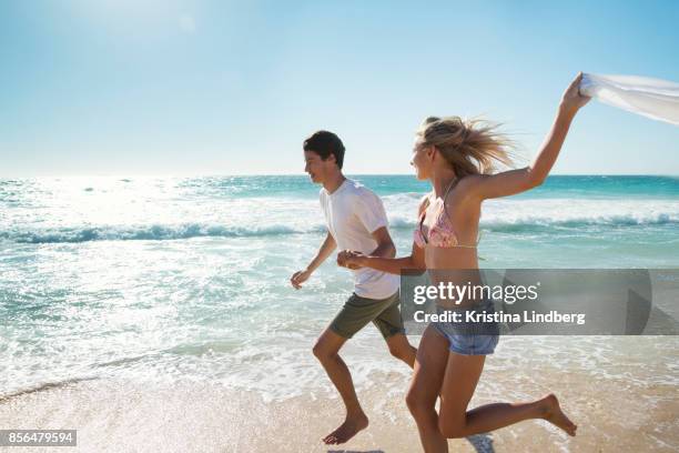 group of friends and coupple walking and hanging out on the beach, waring shorts and tops - running shorts foto e immagini stock