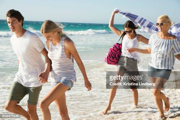 group of friends and coupple walking and hanging out on the beach, waring shorts and tops - sleeveless stock pictures, royalty-free photos & images