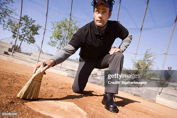 umpire sweeping off home plate - backstop foto e immagini stock