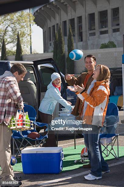 friends tossing football at tailgate party - tailgate party stock pictures, royalty-free photos & images