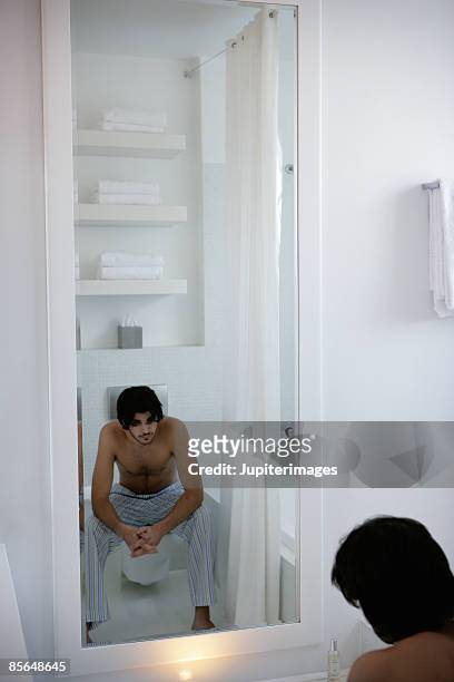 man sitting on toilet and looking in the mirror wearing paja - paja stock pictures, royalty-free photos & images