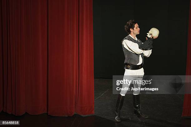 actor holding skull on stage - acteur stockfoto's en -beelden