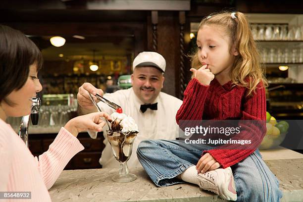 girls tasting ice cream sundae with finger - fudge sauce stock pictures, royalty-free photos & images