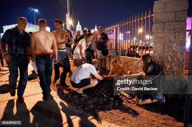 People tend to the wounded outside the Route 91 Harvest Country music festival grounds after an apparent shooting on October 1, 2017 in Las Vegas,...