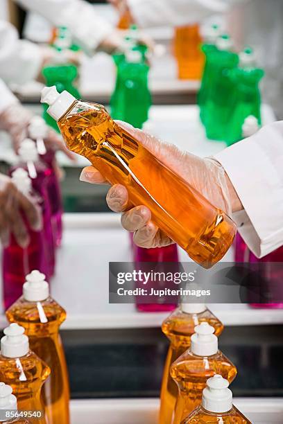 workers in factory with bottles of dishwashing liquid - spülmittel stock-fotos und bilder