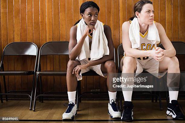 women basketball players sitting on sidelines - basketball sideline stock pictures, royalty-free photos & images