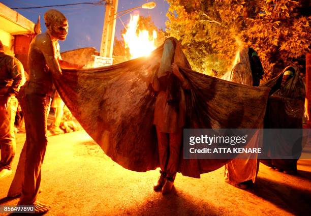Iranian Shiite Muslim women gather around a bonfire after rubbing mud on their body during the 'Kharrah Mali' ritual to mark the Ashura religious...
