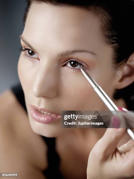 woman applying eyeliner - eye liner stock-fotos und bilder