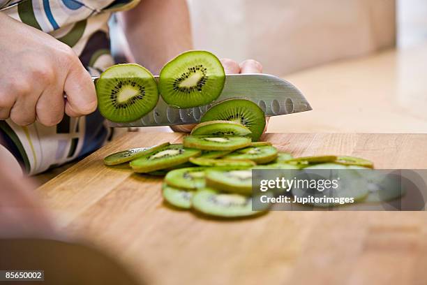 hand slicing kiwi - kiwi fotografías e imágenes de stock