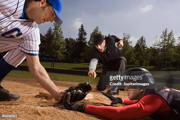 baseman tagging and umpire signaling strike out to baseball player - baseball umpire fotografías e imágenes de stock