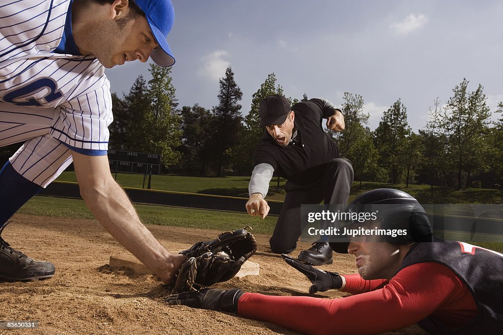 Baseman tagging and umpire signaling strike out to baseball player
