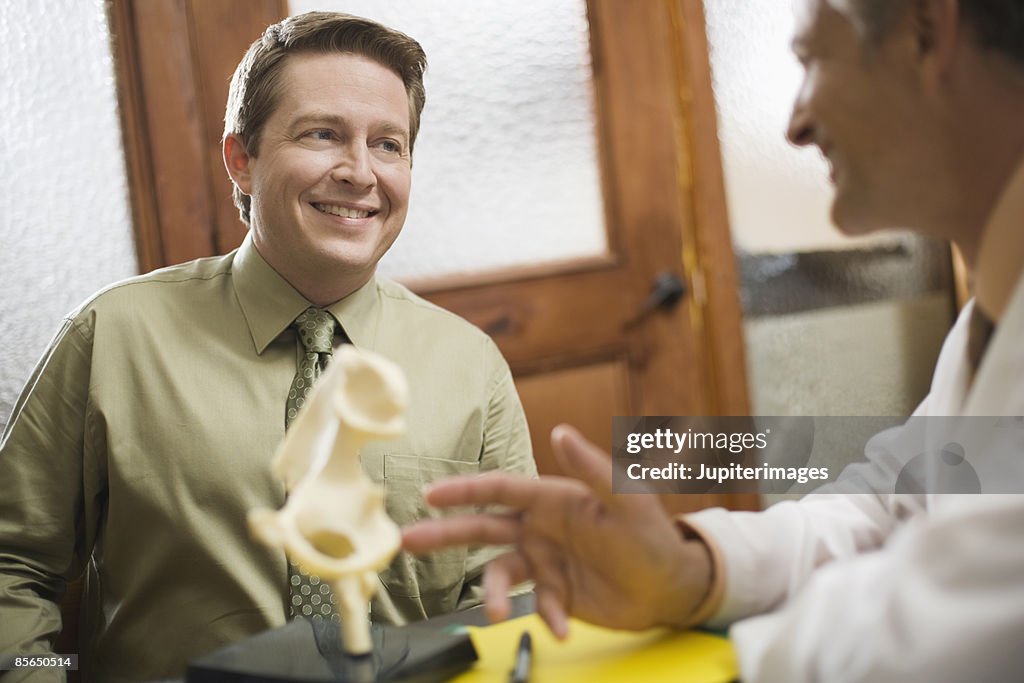 Man and doctor in office with model of hip bone