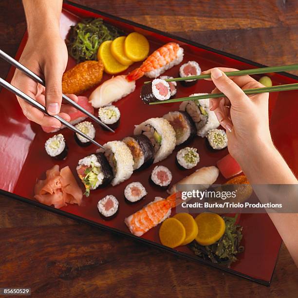 hands eating sushi with chopsticks - inarizushi stock-fotos und bilder