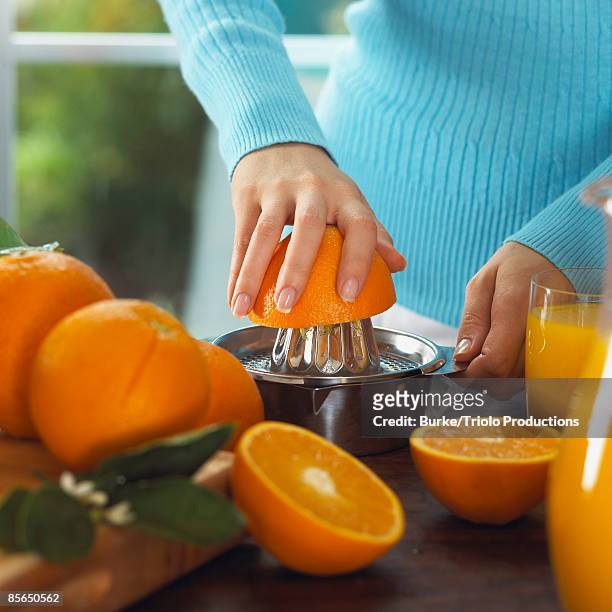 woman squeezing oranges into orange juice - orange juice stock pictures, royalty-free photos & images