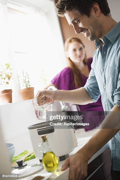 man pouring water into rice cooker - water in measuring cup stock pictures, royalty-free photos & images